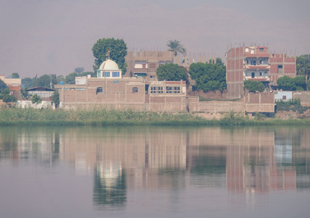 Small city of AZ Zawayah in Qena Governate of Egypt by side of Nile River with misty heat haze over the riverの写真素材