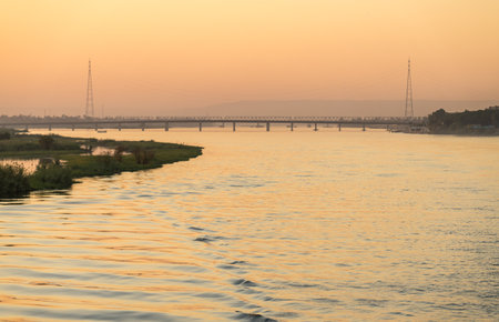 Wake of cruise ship on River Nile as it leaves Qena and road bridge to sail south to Luxorの写真素材