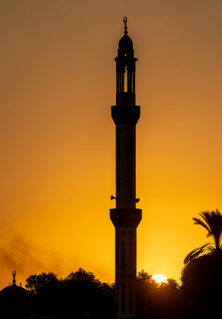 Minaret of a Mosque silhouetted against brilliant sunset sky along Nile River in Egyptの写真素材