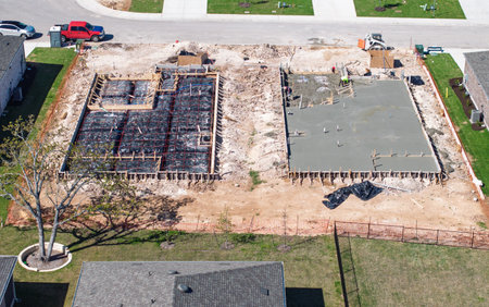 Overhead view of two construction sites, one with a concrete slab and the other a framed foundation ready for concreteの写真素材