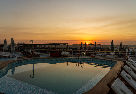 Sun rises over the swimming pool on deck of Nile cruise boat docked alongside another ship in Edfu Egyptの写真素材