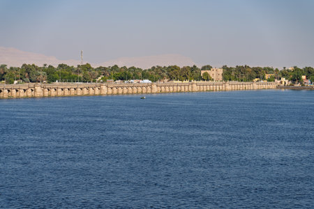 Old Esna dam and lock across the Nile River with sandy hills of Sahara desert behindの写真素材