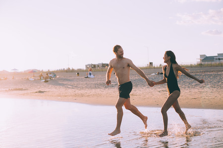 a couple is running on beach while the sun is setの写真素材