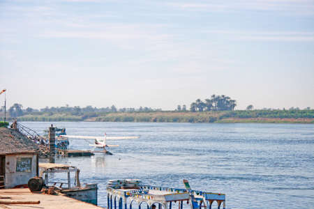 Airplane on the water of the Nile river near the sea pier and ship in Egypt in Africaの写真素材