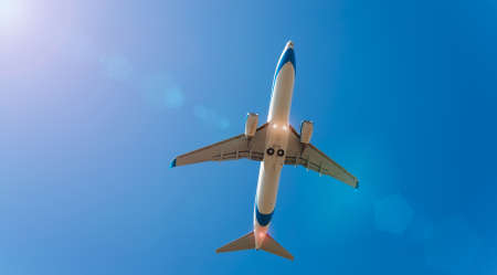 white plane in the blue sky with sun raysの写真素材