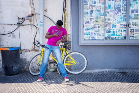 TEL AVIV, ISRAEL - JUNE 5, 2015: Man on a bicycle looking at the phone in the old city of Tel Aviv. June 5, 2015. Tel Aviv, Israel.のeditorial素材
