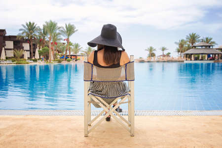 woman in black hat looks at the poolの写真素材