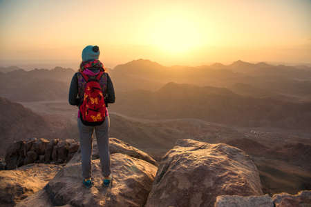 girl looking at the sunrise over the mountainsの写真素材