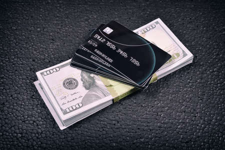 Black credit cards and a pack of dollars on a black background