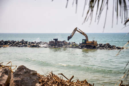 tractor and excavator work together near the waterの写真素材