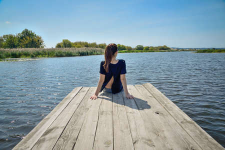 girl on a wooden pier looks at the riverの写真素材