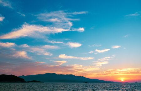 beautiful sunset over the sea on a background of mountainsの写真素材