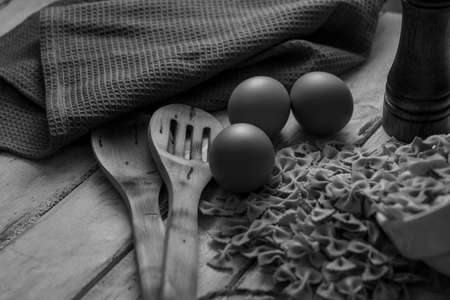 dry pasta on rustic wood and fresh eggs in black and whiteの写真素材
