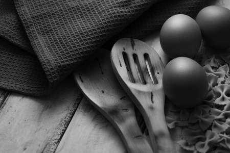 dry pasta on rustic wood and fresh eggs in black and whiteの写真素材
