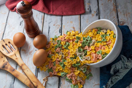 colorful dry noodles on rustic table next to eggs and pepper