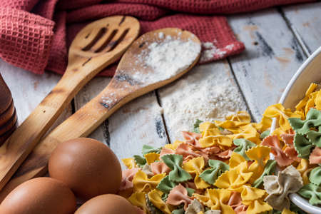 colorful dry noodles on rustic table next to eggs and pepper