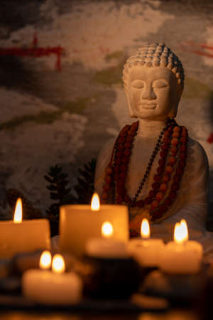 Buddha statue with burning candles in the background. Selective focus.