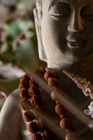 Buddha statue with incense sticks and flowers close-upの写真素材