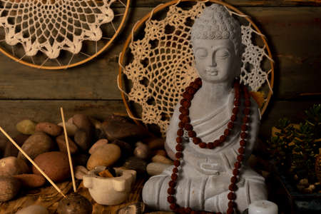 Buddha statue with beads on a wooden background. Boho style.の写真素材