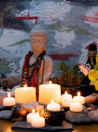 Buddha statue with burning candles on wooden background. Religion concept.の写真素材