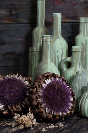 Artichoke flowers in vases on rustic wooden background.の写真素材