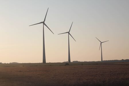 Three windmills, wind turbines standing in the field in the sunsetの写真素材