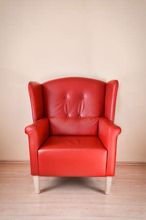 Red leather armchair against the wall on wooden floorの写真素材