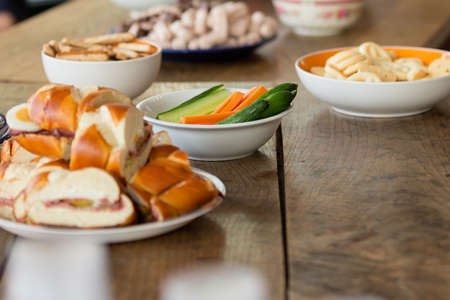 Closeup view of various plates and bowls with snacks on rustic wooden table  Selective focus on the...