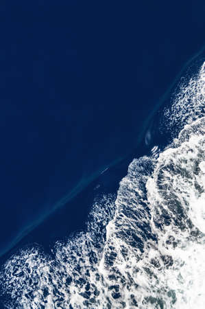 Bird's eye view of a bow wave with slight motion blur and dark ocean surface.の写真素材