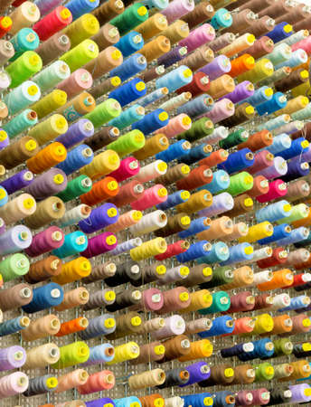 Organized wall of spools with sewing threads in many color variations