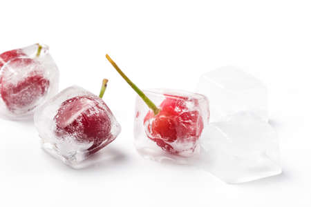 Frozen cherries and ice cubes on white backgroundの写真素材