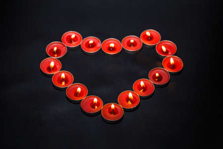 Burning heart-shaped candles on black backgroundの写真素材