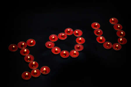 Words I LOVE YOU formed by burning candles on black backgroundの写真素材