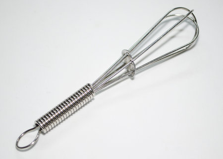 Metal whisk for whipping eggs on a white background, close-upの写真素材