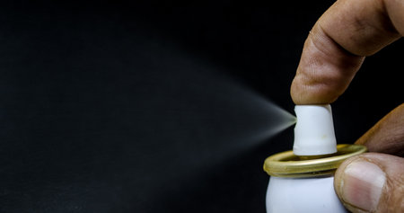 Close up view of a man spraying, A spray can in a hand on a black background Close-upの写真素材