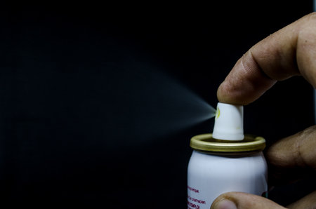 Close up view of a man spraying, A spray can in a hand on a black background Close-upの写真素材