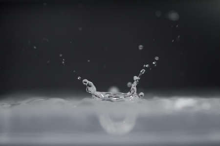 droplet fell into water with splash on black backgroundの写真素材