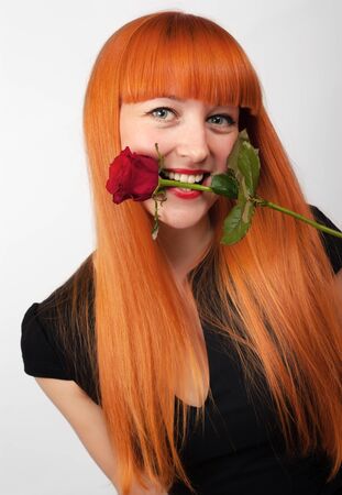 Sexy passionate woman with bright hair holding a rose in her mouthの写真素材