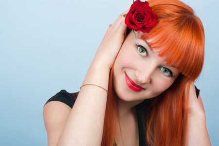 Portrait of beautiful red-haired girl with a rose in her hairの写真素材