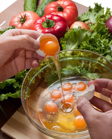 Hands of man break the eggs into a bowl for cooking omeletsの写真素材