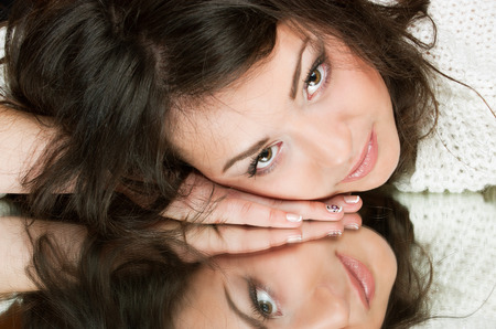 sensual brunette girl lies on a mirror, reflecting in itの写真素材