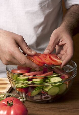 Man puts all the ingredients in a salad close upの写真素材
