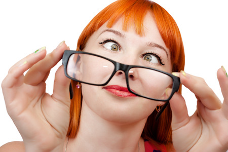 Funny red-haired girl in glasses grimaces on a white backgroundの写真素材