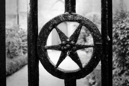 A star shaped detail of a cast iron gate in front of a ancient churchの写真素材