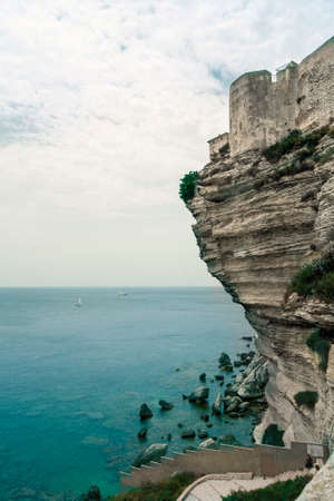 High white cliffs at the coast of Corsica, Bonifacio. The citadel stands high on the rocks. The sky is blue and light overcast.の写真素材