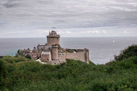 Strong castle or fortress on a green overgrown mountain at the beach of France in summer.の写真素材