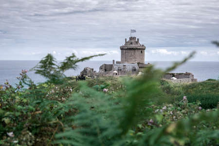 Strong castle or fortress on a green overgrown mountain at the beach of France in summer.の写真素材