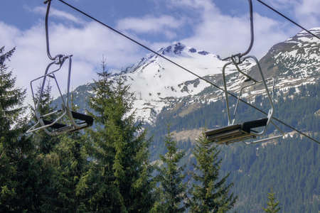Two empty seats of a ski-lift against the background of mountains and snowの写真素材