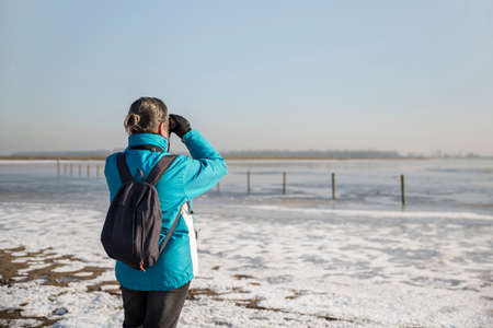 Woman looking through binocularsの写真素材