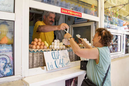 A Romanian woman is buying a sack of eggs from a market salesman in Bucharest.のeditorial素材